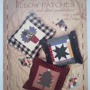 Op de afbeelding: Een hobbyboek getiteld Pillow Patches and other possibilities door Nancy J. Smith en Lynda S. Milligan. De kaft toont drie vierkante kussens met knoopaccenten, voorzien van stoffen applicaties van bloemen, een ster en een boom.