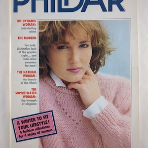 May include: A magazine cover with the title "PHILDAR" in blue. The cover features a woman in a pink knitted sweater. Text on the cover advertises winter fashion collections. The overall design has a vintage, retro style.