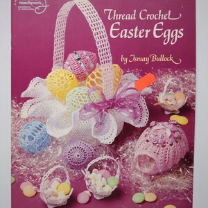 May include: A book cover showing thread crochet Easter eggs. The cover has a pink background with a white crocheted basket filled with colourful crocheted eggs. The text reads "Thread Crochet Easter Eggs by Ismay Bullock."
