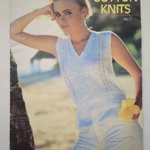 以下が含まれることがあります： THOROBRED scheepjeswolによるヴィンテージの編み物パターンブックレット「COTTON KNITS No. 1」。表紙には、Vネックの白いノースリーブニットトップが描かれており、縦方向のレースのディテールが施され、白いショートパンツと黄色い花が添えられています。