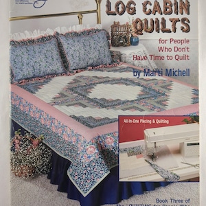 May include: A book cover titled "Weekend Log Cabin Quilts" by Marti Michell. The cover features a completed quilt on a bed with matching pillows. The quilt has a pink and blue floral border and a log cabin design. The book is part of the "Quilting for People Who Don't Have Time to Quilt" series.