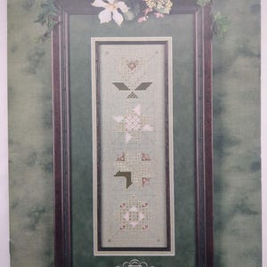 May include: A Cross 'N Patch Another Story Number 124 cross stitch pattern booklet featuring a vertical sampler design with four geometric motifs in shades of pink, green, and white, framed by a dark border with floral accents at the top.