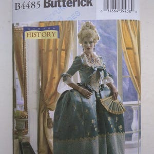 Puede incluir: Un sobre de patrón de costura Butterick B4485 para un disfraz histórico. La portada muestra a una persona con un vestido azul con estampado floral, falda ancha, adornos de encaje y una peluca alta empolvada. El texto dice Butterick B4485 y Making History.