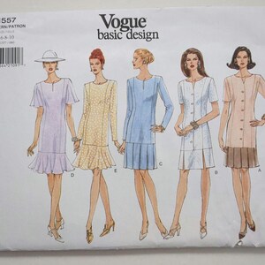Könnte beinhalten: Ein Vogue basic design Schnittmusterumschlag, Nummer 1557, für die Größen 6-8-10. Die Vorderseite zeigt fünf Illustrationen von Kleidern in verschiedenen Stilen, darunter kurze und lange Ärmel, einige mit Faltenröcken und andere mit ausgestellten Säumen.