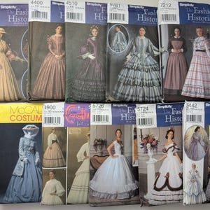 May include: A collection of twelve sewing pattern envelopes from Simplicity and McCall's, featuring illustrations of historical-style dresses and gowns. Each envelope displays a unique garment design, model photographs, brand logos, and product codes.