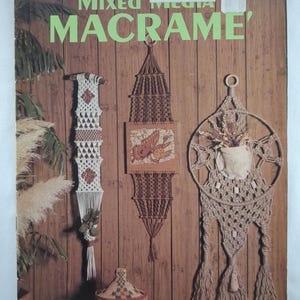 May include: A vintage book cover titled "Mixed Macrame" showcasing macrame wall hangings and decorative items. The cover features macrame designs in brown and cream hues, set against a wooden backdrop. The Canadian price is $2.49.