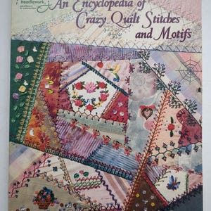 Könnte beinhalten: Ein Softcover-Buch mit dem Titel An Encyclopedia of Crazy Quilt Stitches and Motifs von Linda Causee, das auf dem Cover einen mehrfarbigen Stoffquilt mit aufwendigen Stickereien, floralen Mustern und verschiedenen Zierstichen zeigt.