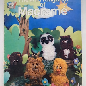 May include: A vintage book cover titled "The Wild Kingdom of Macrame" featuring a colorful illustration. The cover showcases a blue sky backdrop with a tree, and several yarn-crafted animal figures, including a panda, lion, and bear.