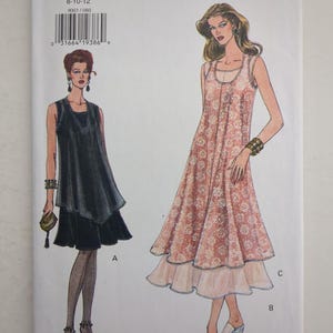 Könnte beinhalten: Ein Very Easy Very Vogue Schnittmusterumschlag 9003 für die Größen 8-10-12. Die Vorderseite zeigt Illustrationen von zwei ärmellosen Kleiderstilen: ein kurzes schwarzes Kleid mit geschichtetem Saum und ein längeres Kleid mit Blumenmuster.