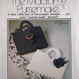 May include: A vintage book cover titled "The Macrame Pursemaker." It features a black macrame purse with a wooden handle and a white macrame purse with a black rose. The book promises a collection of purse designs. The author is Rose Brinkley.