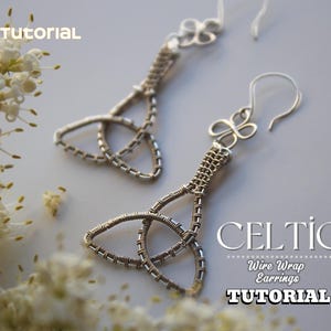 Può includere: Un paio di orecchini celtici in filo d'argento. Gli orecchini presentano un design a nodo celtico e sono esposti su una superficie grigio chiaro con fiori bianchi. Il testo sull'immagine recita "PDF Tutorial" e "Celtic Wire Wrap Earrings Tutorial."