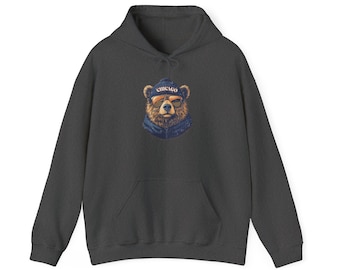 May include: Dark gray hoodie featuring a graphic of a bear wearing sunglasses and a beanie with "CHICAGO" printed on it. The bear has a blue scarf. The hoodie has a kangaroo pocket and a drawstring hood.