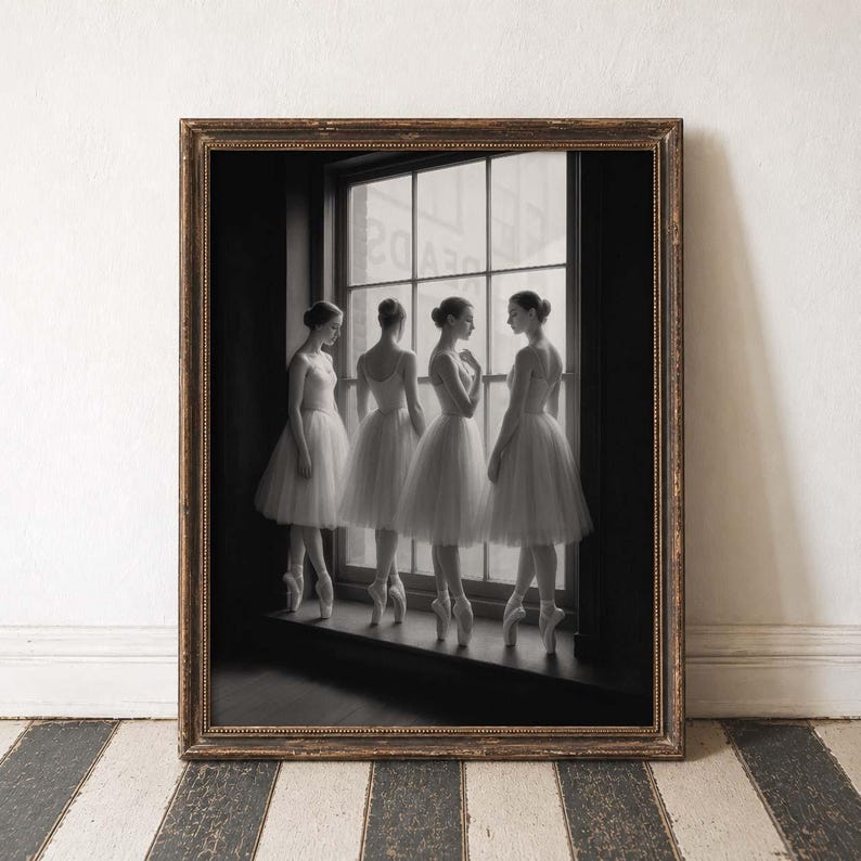 May include: A framed black and white print featuring four ballerinas in white tutus and pointe shoes, standing by a window. The print has a dark brown, ornate frame and is set against a white wall and a black and white striped floor.