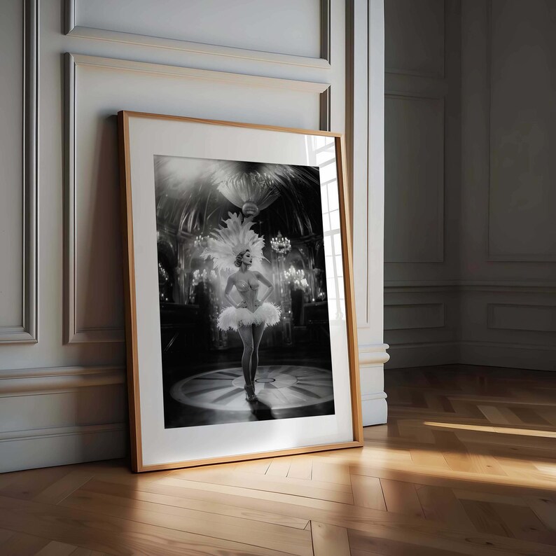 May include: Black and white framed print of a showgirl in a feathered headdress and tutu, standing on a stage. The image is set in a vintage theater with chandeliers and spotlights.