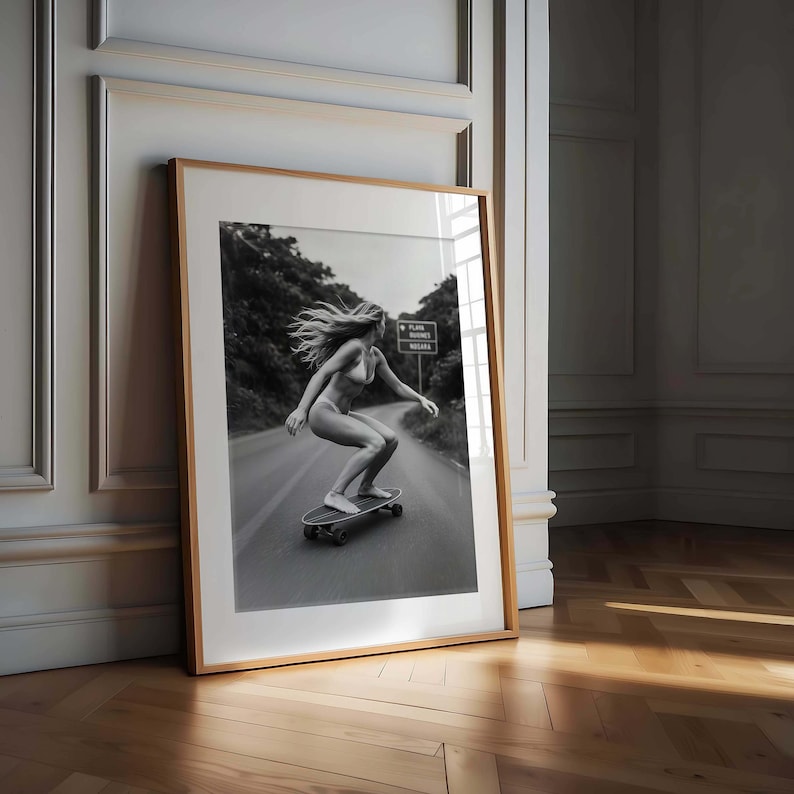 Peut inclure: Tirage encadr&eacute; en noir et blanc d'une personne faisant du skateboard sur une route. La personne porte peu de v&ecirc;tements et a les cheveux longs. Un panneau routier est visible en arri&egrave;re-plan. Le tirage est dans un cadre en bois.