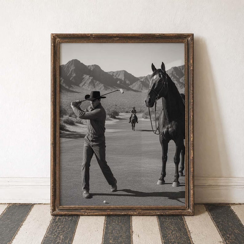 May include: Black and white framed print of a man swinging a golf club on a golf course, with a horse standing nearby. The background features mountains and another person riding a horse. The frame has a gold-colored trim.