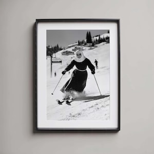 May include: A black and white photograph of a woman wearing a nun's habit skiing down a snowy slope. She is wearing a white head covering and a black robe. She is holding ski poles and is smiling.