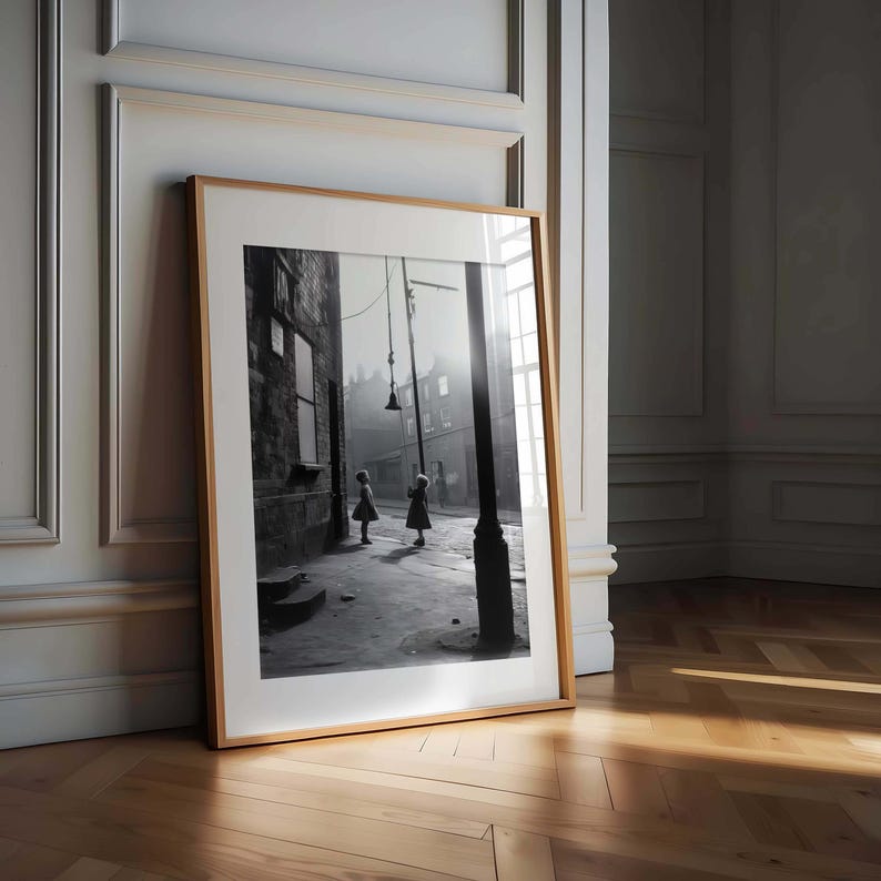 May include: Black and white photograph of two girls playing in a street with a lamppost in the background.