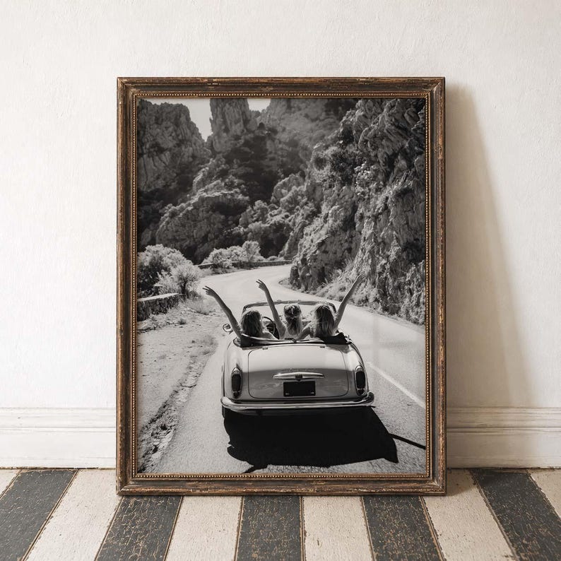 Puede incluir: Impresi&oacute;n enmarcada en blanco y negro de un coche descapotable cl&aacute;sico en una carretera de monta&ntilde;a. Tres personas con los brazos en alto en el coche. El marco es dorado oscuro con detalles ornamentales.