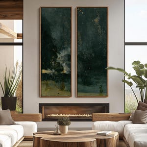May include: Two vertical abstract paintings in wooden frames. The artwork features dark teal and gold tones, with a textured, atmospheric effect. The paintings are displayed above a fireplace in a modern living room setting.