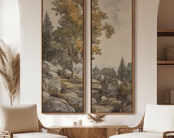 May include: Two framed landscape art prints. The artwork features a watercolor-style depiction of a forest scene with trees, rocks, and a path. The color palette includes greens, browns, and grays, with a neutral background. The frames are a warm brown color.