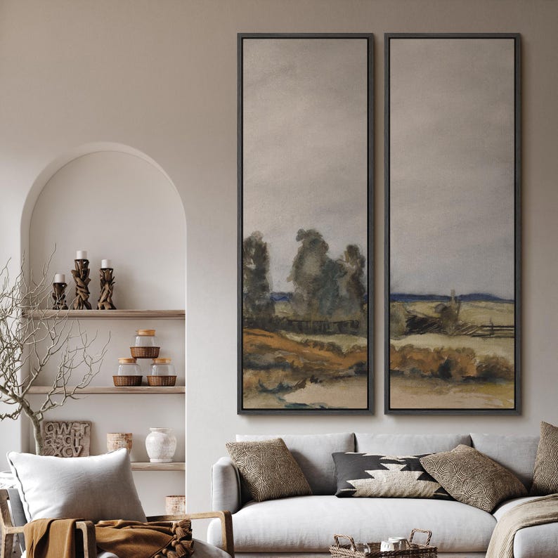 May include: Two framed landscape paintings with a muted color palette. The artwork depicts a rural scene with trees, fields, and a fence. The frames are dark, and the overall aesthetic is rustic and serene, suitable for home decor.