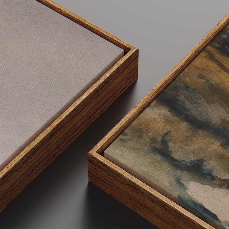 May include: Two framed canvas art pieces. One canvas is a solid light gray color, and the other features a watercolor painting with brown, blue, and tan hues. Both are set in wooden frames.