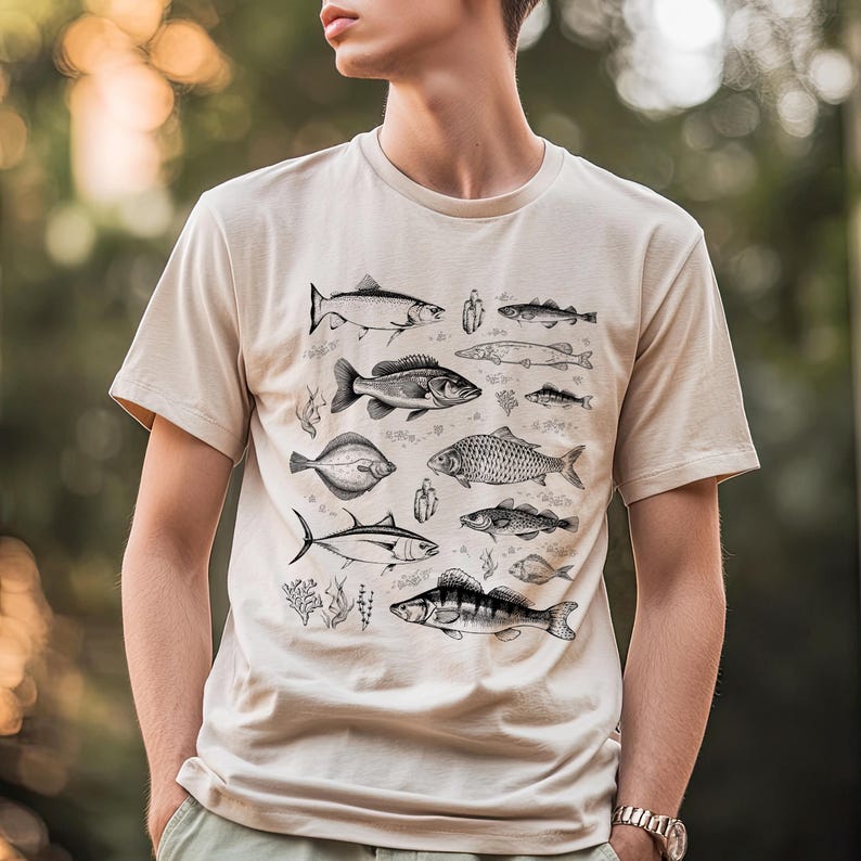 Puede incluir: Camiseta beige con una ilustraci&oacute;n detallada en blanco y negro de varias especies de peces. El dise&ntilde;o incluye diferentes tipos de peces, algas marinas y otros elementos acu&aacute;ticos. La camiseta tiene mangas cortas y cuello redondo.