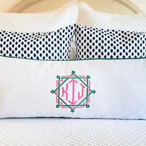 May include: A rectangular white lumbar pillow featuring a green and pink embroidered monogram with the letters KIJ centered within a geometric frame. The pillow has a dark green piped edge and a textured fabric finish, presented horizontally.