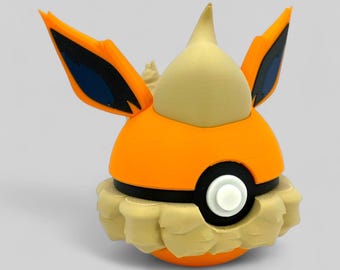 May include: A 3D-printed orange and tan figure resembling a character from a popular animated series. The figure has large, pointed ears with black and blue accents, a cream-colored head, and a ruffled base. A black and white circle is on the front.