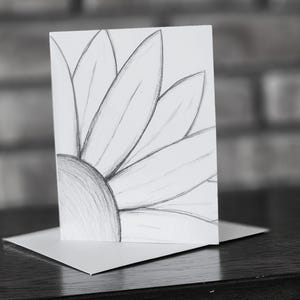 May include: A black and white pencil drawing of a flower on a white card. The flower is drawn in a simple style with a few petals.