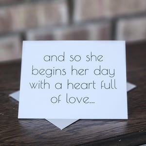 May include: A white card with the text "and so she begins her day with a heart full of love..." printed in black.
