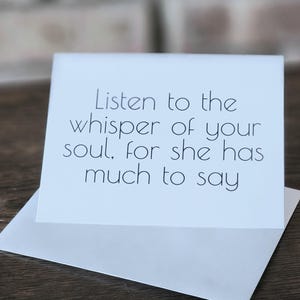 May include: White card with black text that reads "Listen to the whisper of your soul, for she has much to say."