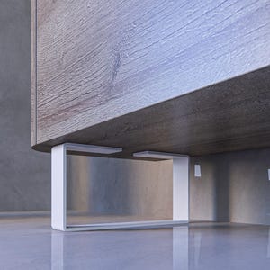 Puede incluir: Un marco de metal blanco con forma rectangular sostiene un armario de madera. El armario tiene un acabado de madera de grano marrón claro.