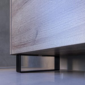 Op de afbeelding: Een houten kast met een lichtgrijze houtnerf. De kast heeft zwarte metalen poten.