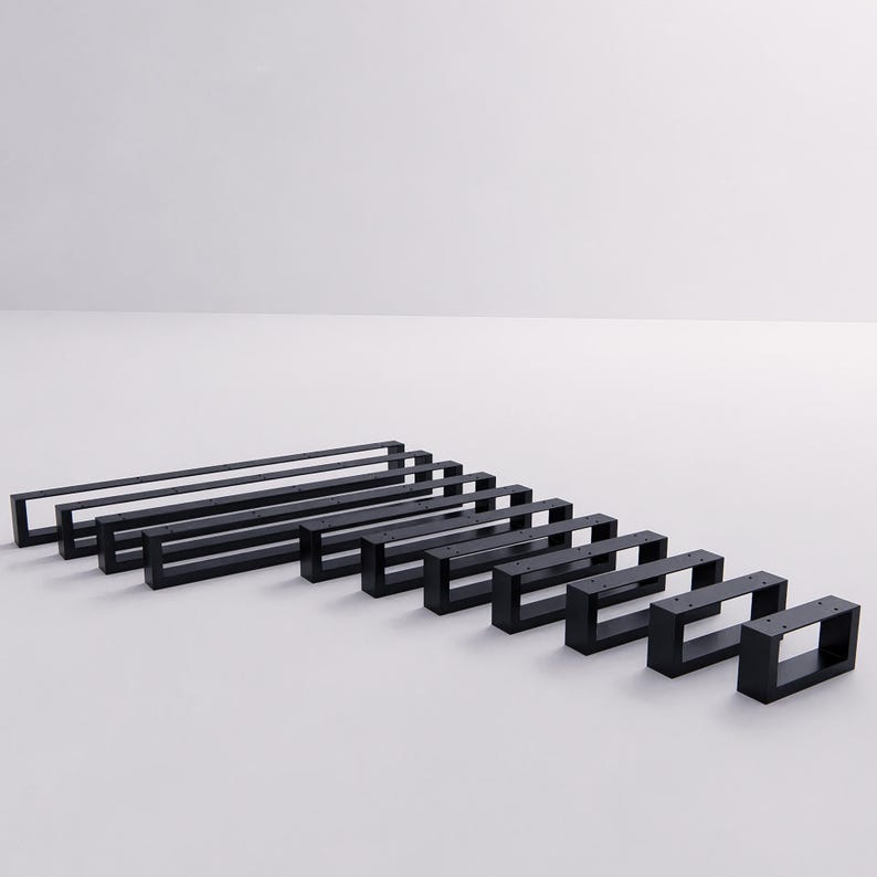 May include: A collection of ten rectangular black metal furniture legs arranged in a row from longest to shortest. Each leg features a hollow, open-frame design with pre-drilled holes along the top horizontal bar for mounting purposes.