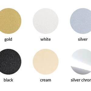 May include: A color chart featuring six circular swatches arranged in two rows. The top row displays gold, white, and silver circles. The bottom row shows black, cream, and silver chrome circles, each labeled with its corresponding color name.
