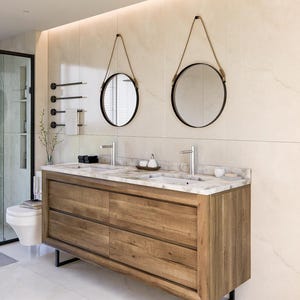 May include: A double vanity cabinet featuring a natural wood finish with four drawers and a white marble countertop. Two rectangular sinks are integrated into the top, paired with two round mirrors suspended by rope and two silver faucets.