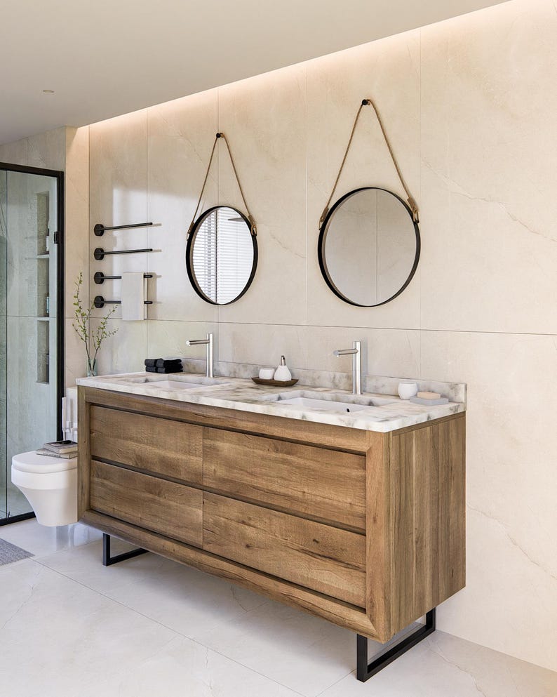 May include: A double vanity cabinet featuring a natural wood finish with four drawers and a white marble countertop. Two rectangular sinks are integrated into the top, paired with two round mirrors suspended by rope and two silver faucets.