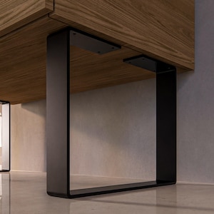 Può includere: Gambe da tavolo in metallo nero con un design quadrato. Le gambe sono fissate a un piano da tavolo in legno.