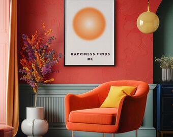 May include: A framed art print with the text "HAPPINESS FINDS ME" hangs above an orange armchair with a yellow pillow. The artwork features an orange gradient circle. A vase with colorful branches sits to the left.