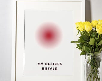 May include: White framed art print featuring a red gradient circle and the text "MY DESIRES UNFOLD" in a decorative font. A bouquet of yellow roses in a glass jar sits to the right of the print.