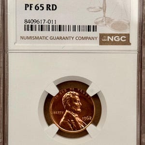 May include: A 1962 Doubled Die Obv 1C penny graded PF 65 RD, encapsulated in a Numismatic Guaranty Company (NGC) holder. The coin features the text "IN GOD WE TRUST" and "LIBERTY", with the year 1962 visible.