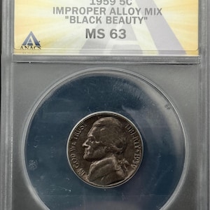 May include: A 1959 5C "Black Beauty" nickel coin, graded MS 63, encased in a clear protective holder. The coin features a profile of Thomas Jefferson and the text "IN GOD WE TRUST" and "LIBERTY 1959". The holder includes the text "1959 5C IMPROPER ALLOY MIX".