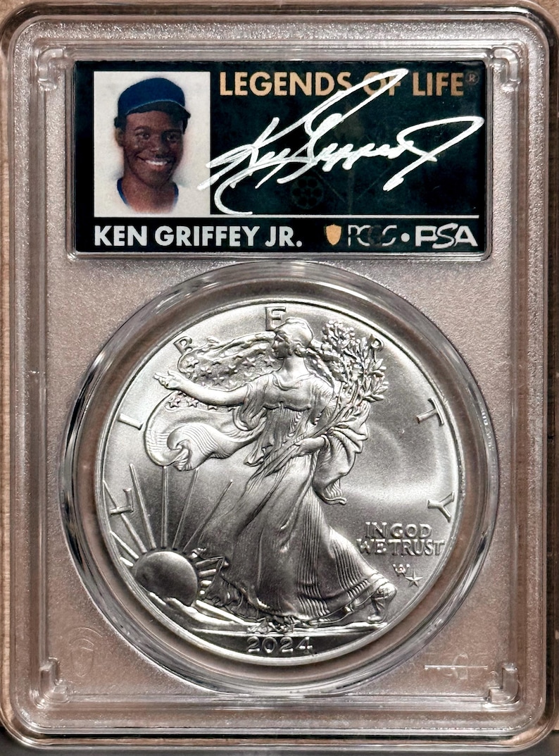 Peut inclure: Un objet de collection class&eacute; comprenant une carte de baseball de Ken Griffey Jr. et une pi&egrave;ce d'argent Walking Liberty de 2024. La carte est dans un bo&icirc;tier de protection avec le texte "LEGENDS OF LIFE" et une signature. La pi&egrave;ce repr&eacute;sente Lady Liberty.