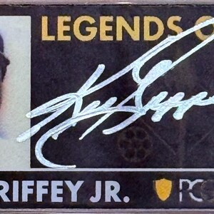 Peut inclure: Carte de collection de baseball avec Ken Griffey Jr. portant une casquette. La carte pr&eacute;sente un portrait de Griffey, une signature et le texte "LEGENDS OF LIFE" et "KEN GRIFFEY JR.". La carte est dans un &eacute;tui de protection.