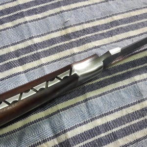 May include: A pocket knife with a brown wooden handle and a silver blade. The blade is partially open and the handle has a decorative pattern.