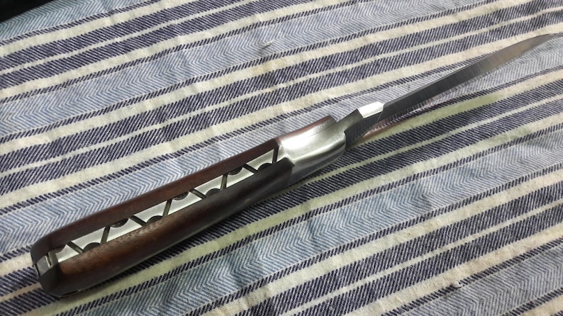May include: A pocket knife with a brown wooden handle and a silver blade. The blade is partially open and the handle has a decorative pattern.