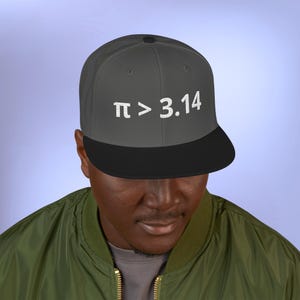 May include: A grey and black baseball cap featuring the embroidered text "π > 3.14" in white. The cap has a flat peak and a structured design, suitable for casual wear.