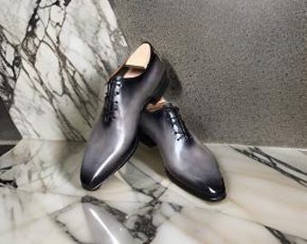Puede incluir: Un par de zapatos de vestir de cuero gris con cordones y punta puntiaguda.